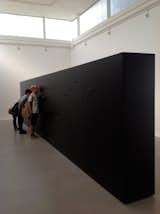 The installation in the Brazil pavilion by Marcio Kogan is a minimal long black monolith with peepholes and speakers.