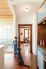 Kitchen, Colorful Cabinet, Wood Counter, and Dark Hardwood Floor To help define the kitchen, the architects designed a wall of storage with cubbies 

on one side and a pantry with appliances on the other. Colorful doors add 

a playful touch, and DP3 Series cabinet pulls from Doug Mockett & Company keep the surfaces streamlined.  Search “hallway” from An Airy Addition to a Historic Boise Home
