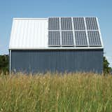 Exterior, Cabin, Metal, Gable, Wood, and Green A 1.4-kW solar array by Sharp and propane-powered in-floor radiant heating from Radiantec obviate any need to connect to municipal power.  Exterior Green Metal Cabin Photos from A Sustainably Built Home in Rural Ontario