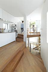 Kitchen, Medium Hardwood Floor, White Cabinet, Pendant Lighting, Wall Lighting, and Microwave The top of the house is dedicated to a dining area and a kitchen outfitted with steel-topped cabinets from Sanwa Company.  Photos from This Sculptural Staircase Shapes an Entire Home