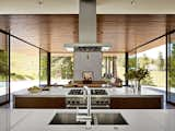 Kitchen, Wood Cabinet, Range, Undermount Sink, and Range Hood All appliances in the kitchen are from Thermador, save for a Miele dishwasher. Bright white Caesarstone bounces yet more light into the space.  Photo 3 of 3 in Living area by Gary Hite from This Couple Achieves Their Glass House Goals