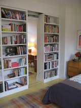 Bookshelf walls in a guest bedroom slide to reveal a small study.