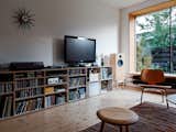The living room strikes more of a mid-century note with its Sunburst clock by George Nelson and an Eames molded plywood lounge chair. The architects added a deep window seat where the kids now play. The window frame also houses a screen which, when rolled down, is used to project movies onto.