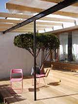 Being on the ground floor has its benefits—namely a bit of outdoor space. The black I-beam supporting the canopy of exposed joists offers a nice contrast to the wood above and below. Pink chairs do the trick as well.