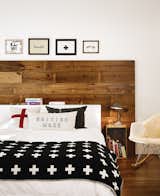 Wide shiplap boards were reclaimed from the renovation of a 1920s bungalow in Austin, Texas. At the head of the bed, the wood acts as a focal point and brings a warmth to the space that's complemented by a rustic bedside table, a sheepskin throw on a chair, and an inviting bed layered with blankets and pillows.