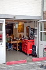 A red mechanics tool chest houses car stuff, while a wood block on wheels contains additional stove burners for extra cooking space.