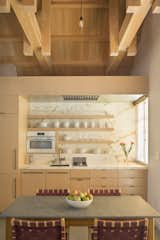 Richardson centered the renovation on a space-efficient "service cube," an eco-wood box that houses a marble kitchen and a bathroom. The dining chairs are by Jens Risom.  Photo 5 of 10 in Kitchen by Emilio Garcia from A Small Loft Sits Above a Renovated Barn in California