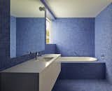 The bathrooms are tiled in bright blue mosaic to offset the home’s limited materials and color palette. The sinks, toilets, and tubs are by Villeroy &amp; Boch, while the faucets and towel rails are by Grohe and Avenir, respectively.