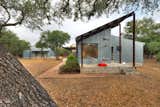 Affordable gestures abound in this transformation of a dilapidated former duplex in the Texas Hill Country. For a cost-conscious 2,000-square-foot renovation located 30 minutes outside of Austin, Texas, architect Nick Deaver took a look around for inspiration. He spied galvanized metal cladding on the region’s sheds and co-opted the inexpensive, resilient material for his own design. He then applied locally quarried Lueders limestone near the entrance—a warm contrast to the steely facade.