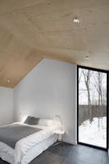 Bedroom, Table Lighting, Bed, and Slate Floor The bedroom’s vertical, floor-to-ceiling window lets occupants admire the graceful trees outside. A Mini Tolomeo lamp by Artemide sits on the bedside table.  Photos from Amazing Cantilevered Home in the Mountains