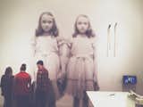 The infamous Grady Twins from The Shining (1980) look unfazed, as a small group of visitors focus on an exhibition reading.