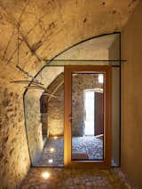 Dramatic floor lighting on this glass wall, custom fit within the curve of a carved-out stone wall, provides simple beauty in material contrast. "In such small spaces, it's often better to integrate the furniture and fixtures into the room," says de Meuron.