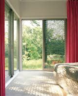 In the master bedroom, the same perforated material that was used in the bathroom gives a sense of sunlight filtering through leaves.