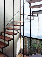 The wood-and-steel open staircase wends its way up three stories, supported by a concrete structural wall embedded with PVC tubes and bare lightbulbs. Read more about this 21st-century Argentine home here.