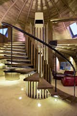 A sweeping spiral staircase occupies the center of the self-supporting dome. Its reclaimed pine treads echo the dome’s ceiling and contrast pleasantly with the raw steel railing. PAK LED lights installed in the floor add an extra touch of drama to the home’s showpiece.  Photo 2 of 8 in A British Furniture Brand Built This Round Village in China