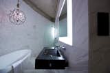 In the Round House’s bathroom, a custom black marble basin protrudes from the white marble-tiled walls. Smaller tiles follow the curve of the house’s outer wall, a curve that is echoed by the sculptural white bathtub, which sits under a Timothy Oulton Gyor crystal chandelier.  Photo 8 of 8 in A British Furniture Brand Built This Round Village in China