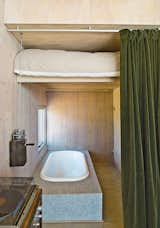 Taking inspiration from train cabins, the guest bed lifts to reveal a bathtub. Garlick made the mechanism using sailboat hardware. The velvet curtain is by Restoration Hardware and the tile is from Stone Tile.