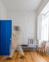The blue entry door packs a punch in the neutral living area, which is sparsely furnished with inexpensive pieces — some from local Portuguese companies, others self-made or purchased in flea markets.  Photo 2 of 9 in Minimal Apartment in Lisbon Divvied Up by Sliding Doors by Laura C. Mallonee