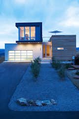 The cantilevered office space above the garage is also underlit with exterior lighting between the driveway and the home. Landscaping is minimal, with native plants that require little maintenance. Water drains through a downspout onto pea gravel.