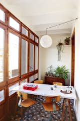 A glazed veranda on the flat’s west side offers a cozy spot to enjoy an espresso. The utilitarian table and chairs were purchased second-hand, while the lamp was custom designed.  Photo 3 of 5 in Perfect Weekend Verandas by Luke Hopping from Historic Details and Playful Modernism Meet in this Stunning Barcelona Flat