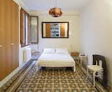 Understated décor in the master bedroom lets the floor tiles fully pop. A pendant lamp designed in 1957 by Spanish modernist architect José Antonio hangs above the bed.  Photo 7 of 8 in Historic Details and Playful Modernism Meet in this Stunning Barcelona Flat