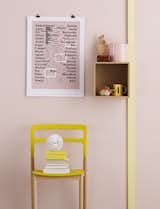 A pink and yellow interior close-up with various ephemera such as a movie director typography poster, paper beehive ball, wooden beads, and a models artist hand sculpture. Photo by: Magnus Anesund
