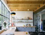 Shane Michael Pavonetti, an Austin-based architect and contractor, and his wife, Holly, built their eco-friendly home on a lean budget of $175,000. The cedar siding used on the exterior reappears throughout the house. Keen on recycling the wood, the couple added shelving to their kitchen as well.&nbsp;