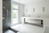 The bathrooms feature the same polished concrete flooring and poured concrete counters found elsewhere in the home. A honed granite recessed shower provides a visual counterpoint to the sea of white and steel.