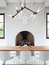 Barbara Hill designed this modern home in Atlanta, Georgia. Its informal dining space has a slightly rustic feel, sporting bronze and wood in the form of a Lindsey Adams Adelman chandelier for Roll & Hill.