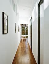 Hallway and Medium Hardwood Floor The interiors are painted in Sherwin-Williams Extra White Flat; flooring is five-inch walnut plank. A bentwood table and chairs are from ECR4Kids.  Photo 9 of 13 in Minimal North Carolina Home Built for a Tech-Forward West Coast Couple