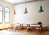 A trio of pastel colored pendants hang above wooden dining furniture inside Harvest.
