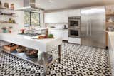 Black and white kitchen floor tiles by Granada Tile are the focal point of this airy, whimsical kitchen. A sizable island of white and stainless steel coordinates nicely with Thermador appliances and white cabinets.