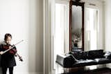 A young girl practices her violin in her living room.