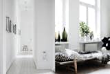 A hallway with white floor boards leads to the living room daybed.