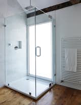 A glass-lined shower with a Hudson Reed shower head adds a modern touch to the second-floor bathroom in this farmhouse renovation. A pane of privacy glass lets natural light enter the room, illuminating the shower stall.