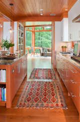 The galley kitchen, which features granite counters with patterns reminiscent of tree branches, is open to the entire first floor including the rear glass tower.