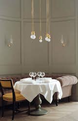 A quintet of Ball Lights hang above a pristinely-set dining table at the Grand Hôtel Stockholm's restaurant, designed by Ilse Crawford.  Photo 5 of 7 in LIGHTING by HOLLY TOMALAK from Lighting Designer We Love: Michael Anastassiades