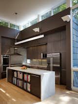 The restrained interior features a custom kitchen with dark cabinetry. Rappe designed it to receed into the space, allowing the views from the window and light streaming through the clerestory to steal the show. He wrapped the island in marble and selected Bosch appliances.