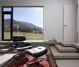 The clients intend to retire to the house. They asked that rooms be constructed flexibly on a non-domestic scale. This one, with an Eames lounge and floor-to-ceiling glass windows, frames a serene mountain vista like a painting.