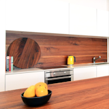 This sleek wood  kitchen counter has a matching wood backsplash designed by Christian Woo.