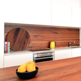 While it's not your traditional backsplash material, when properly prepared and treated, wood can make for an effective, functional, and beautiful backsplash. Here, the wood backsplash matches the wood of the nearby kitchen island in an otherwise white kitchen with white cabinetry.