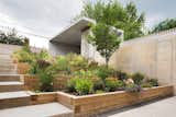 The backside of the lot was dug out to create a recessed garden for privacy. The mother is an active cook, so including planter boxes for herbs and hot peppers was a must.  Photo 15 of 28 in Outdoor. by Connor Beebe from Three Unique Homes Fit Under One Roof for an Extended Family in Queens