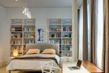 In the master bedroom, a small workstation is accented by a Philippe Stark desk chair, and repurposed white shelving offers generous display space. Ten foot ceilings and expansive windows add to the open and airy feel of the room.