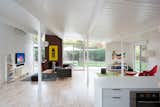 Built in the early 1970s, the house's kitchen, living, and dining areas were originally divided into three distinct zones. In order for this great room to flow as one, Klopf Architecture removed the glass doors and solid walls separating the enclosed atrium from the kitchen and living room.  A Herman Miller trade poster, Design Within Reach book tower, and IKEA sofa mingle in the space.