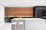 An illuminated brick wall makes a lovely backdrop when juxtaposed against this kitchen's glossy black cabinets.&nbsp;