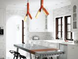 Designer Barbara Hill applies her polished take on minimalism to this traditional 1920s abode in Atlanta for a transplanted Houston family. Hill had the overhead lighting in the kitchen customized by Rich Brilliant Willing in a pert orange that accents the primarily black-and-white interior scheme. She added a stainless steel kitchen island by Bulthaup, its glossiness and “clean feel” tempered by the plastic stacking stools designed by Konstantin Grcic for Magis. The cabinets, appliances, countertops, and marble tile were kept as-is, with the addition of several coats of white paint in order to blend seamlessly with the walls. Photo by Gregory Miller. See the rest of this surprisingly modern Atlanta house on Dwell.com.