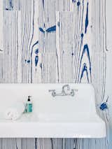 White-and-blue, wood-grain–patterned UonUon tiles by 14oraitaliana line the bathroom walls in a loft above the garage.