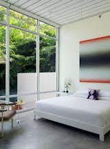 Bedroom, Bed, Chair, Night Stands, Track Lighting, and Concrete Floor In the master suite, a painting by Eric Freeman hangs over a West Elm bed.  Photo 7 of 13 in This Sparkling New Home Is a Perfect Remake of Classic Sarasota School Modernism