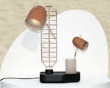 The Standard Table Lamp, made from copper, leather, and acrylic, lacks one thing—an on-off switch. To turn the lamp on, the user must choose a light from two fixtures (one large and one small) and place it in the copper tower.