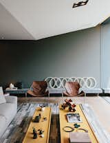 In the sitting area, two leather Paulistano chairs by Paulo Mendes da Rocha top a rug by Yerra; the wall paint is Comex.